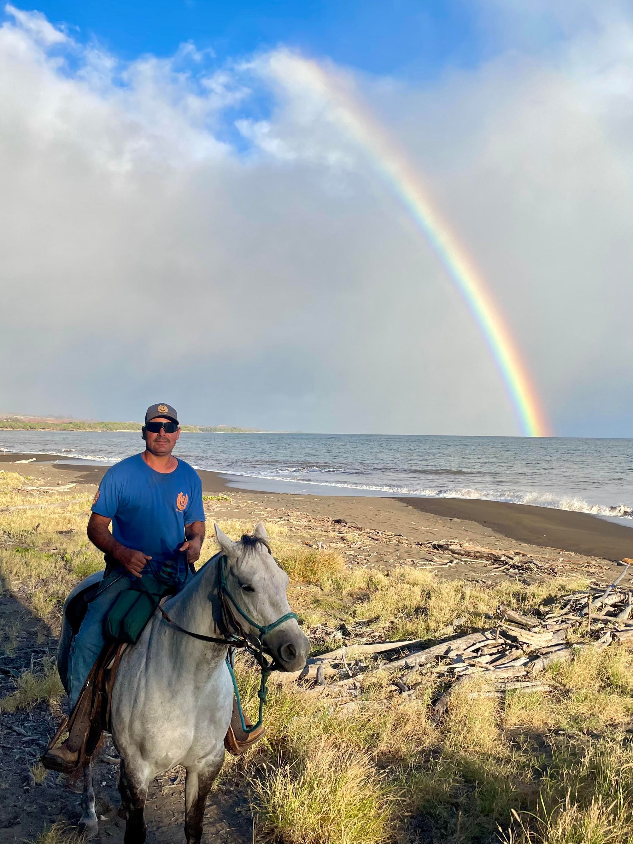 Ranch2 Man on horse near beach with rainbow in the sky.